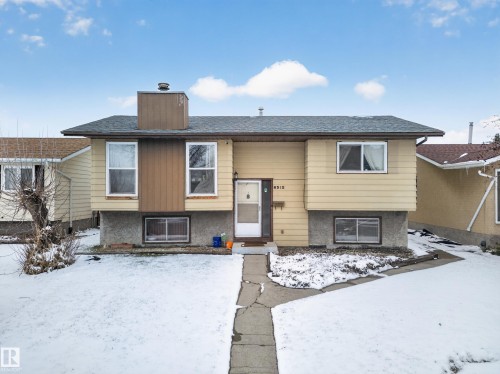 Split-level residence featuring a prominent chimney, horizontal siding, and a concrete walkway - 8312 29 Ave Nw, Edmonton, AB - Outdoor