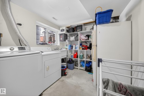 Dedicated laundry area featuring a window, built-in shelving, a utility sink, and concrete flooring - 8312 29 Ave Nw, Edmonton, AB - Indoor Photo Showing Laundry Room