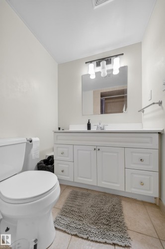 Bathroom featuring a white vanity with panel cabinetry and silver hardware, a rectangular mirror, and a three-light fixture - 8312 29 Ave Nw, Edmonton, AB - Indoor Photo Showing Bathroom
