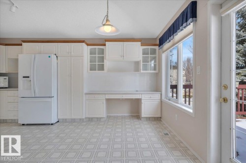 The kitchen features white cabinetry, a built-in desk area, and a white refrigerator - 19 1203 Carter Crest Road, Edmonton, AB - Indoor
