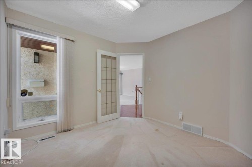 This room features light-colored carpeting, a window offering views of the exterior, and a door with glass panels - 19 1203 Carter Crest Road, Edmonton, AB - Indoor