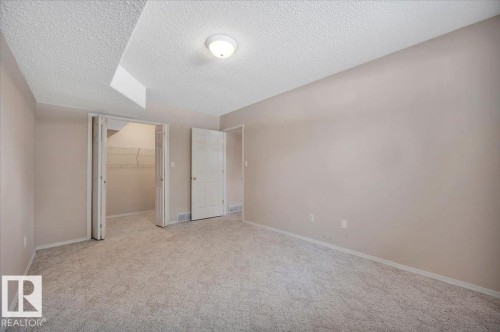 Spacious room featuring neutral carpeting, light-colored walls, a ceiling-mounted light fixture, and a closet with bifold doors - 19 1203 Carter Crest Road, Edmonton, AB - Indoor Photo Showing Other Room