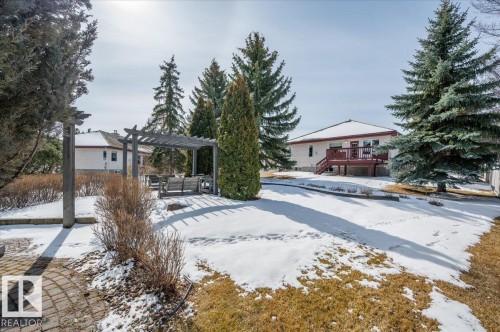 with mature evergreen trees and a wooden pergola, offering an inviting outdoor space - 19 1203 Carter Crest Road, Edmonton, AB - Outdoor With Deck Patio Veranda