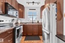 Kitchen featuring wood-finish cabinetry, stainless steel appliances, and a window above the sink - 13516 104A Street, Edmonton, AB  - Indoor Photo Showing Kitchen 