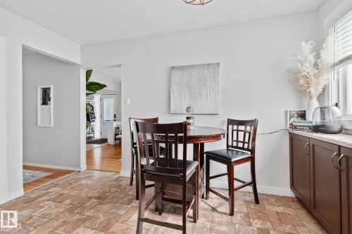 Dining area featuring a round wood-finish table with four matching bar-height chairs, light-colored walls, and patterned tile flooring - 13516 104A Street, Edmonton, AB - Indoor Photo Showing Dining Room