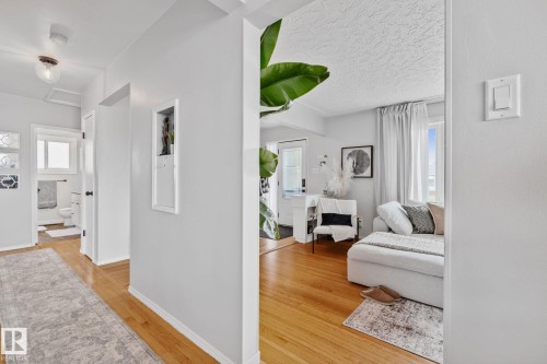Hardwood flooring extends from the living space into the hallway - 13516 104A Street, Edmonton, AB - Indoor With Fireplace