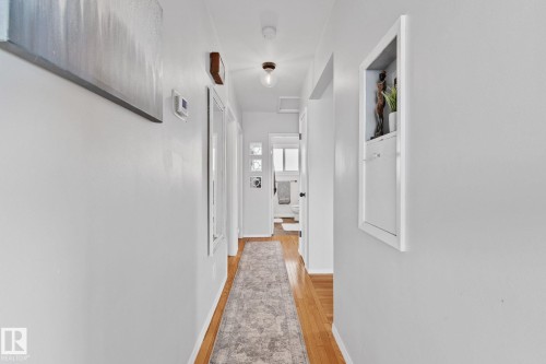 Hallway featuring wood-finish flooring, light grey walls, and a built-in wall niche with storage - 13516 104A Street, Edmonton, AB - Indoor Photo Showing Other Room