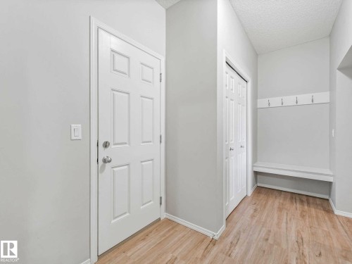 Entryway featuring wood-finish flooring, a six-panel door, built-in coat hooks, and a built-in bench - 2435 12 Avenue, Edmonton, AB - Indoor Photo Showing Other Room