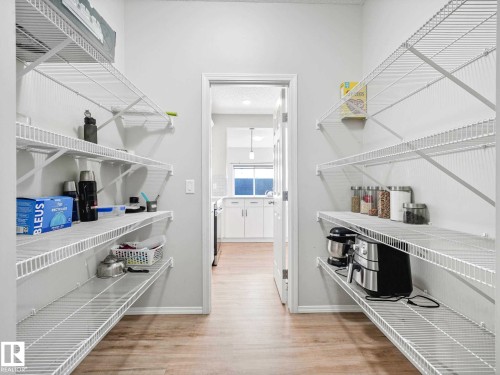 Walk-in pantry featuring light wood-finish flooring, white walls, and extensive wire shelving - 2435 12 Avenue, Edmonton, AB - Indoor With Storage