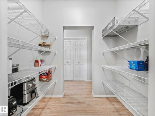 Walk-in pantry featuring wire shelving, light wood-finish flooring, and a neutral wall color - 2435 12 Avenue, Edmonton, AB - Indoor With Storage
