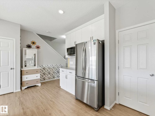 Kitchen area featuring white cabinetry, a stainless steel refrigerator, and a built-in microwave - 2435 12 Avenue, Edmonton, AB - Indoor