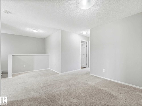 Carpeted landing area featuring a white painted half-wall railing, two flush mount ceiling lights, and light gray wall paint - 2435 12 Avenue, Edmonton, AB - Indoor Photo Showing Other Room