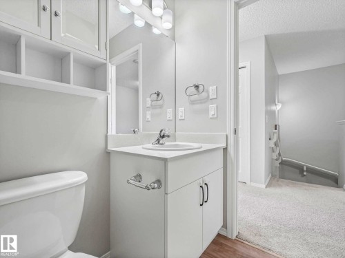Bathroom featuring a white vanity with integrated sink, chrome faucet, wall mirror, and overhead lighting - 2435 12 Avenue, Edmonton, AB - Indoor Photo Showing Bathroom