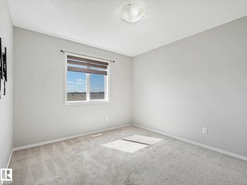Neutral gray carpeted room featuring a white window frame with integrated blinds, a flush-mount ceiling light fixture, and white painted walls - 2435 12 Avenue, Edmonton, AB - Indoor Photo Showing Other Room