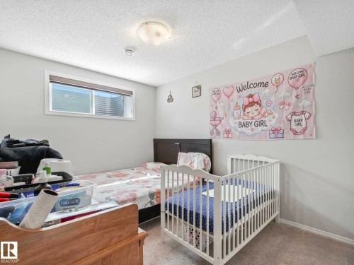 Neutral-toned room featuring light gray walls, plush carpet flooring, and a single window with blinds and a window well visible - 2435 12 Avenue, Edmonton, AB - Indoor Photo Showing Bedroom