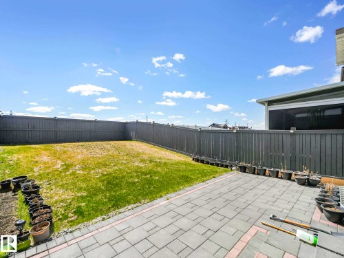 Expansive backyard featuring a manicured lawn area, durable privacy fencing, and a paver patio with a brick border - 2435 12 Avenue, Edmonton, AB - Outdoor With Backyard
