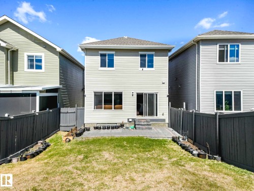 Rear exterior featuring light-colored siding, a multi-pane sliding glass door, and a ground-level patio - 2435 12 Avenue, Edmonton, AB - Outdoor With Exterior