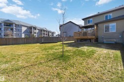 Expansive backyard featuring a manicured lawn, full wooden privacy fencing, a raised wooden deck with a gazebo structure, and established plantings - 