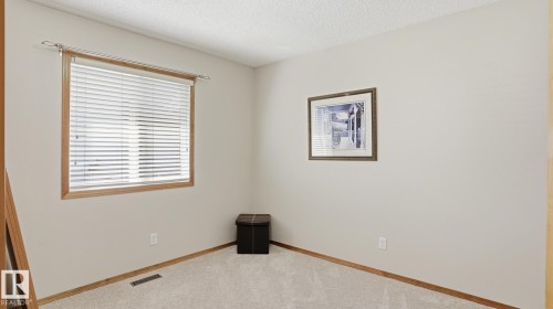 Carpeted room featuring a window with wood trim and horizontal blinds, light-toned walls, and wood baseboards - 5 Richelieu Place, Beaumont, AB - Indoor Photo Showing Other Room