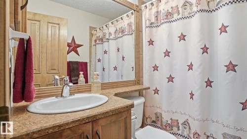 Bathroom featuring a vanity with an oval sink, chrome faucet, and wood-finish cabinetry - 5 Richelieu Place, Beaumont, AB - Indoor Photo Showing Bathroom
