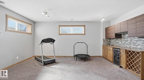 Spacious room featuring carpeting, recessed windows with wood trim, and track lighting - 5 Richelieu Place, Beaumont, AB - Indoor Photo Showing Other Room
