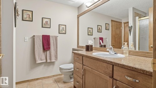 Bathroom vanity with integrated sink and chrome faucet, set against a large framed mirror - 5 Richelieu Place, Beaumont, AB - Indoor Photo Showing Bathroom