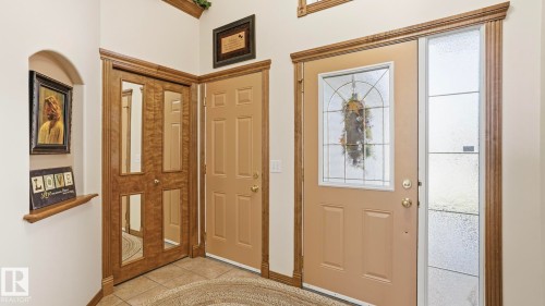 Entryway featuring a decorative front door with leaded glass, an adjacent sidelight with textured glass, and a paneled interior door - 5 Richelieu Place, Beaumont, AB - Indoor Photo Showing Other Room