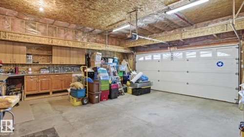 Spacious garage featuring a concrete floor, built-in cabinetry, and a large overhead door with transom windows - 5 Richelieu Place, Beaumont, AB - Indoor Photo Showing Garage