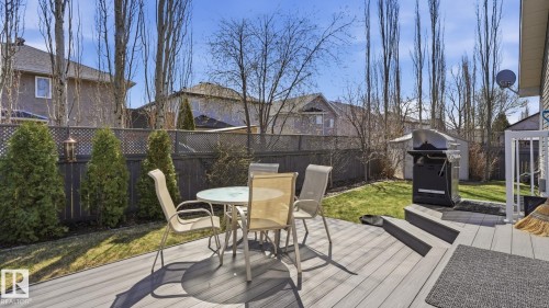 Outdoor decking area featuring composite decking, steps to the grassy yard, a privacy fence, and mature landscaping - 5 Richelieu Place, Beaumont, AB - Outdoor