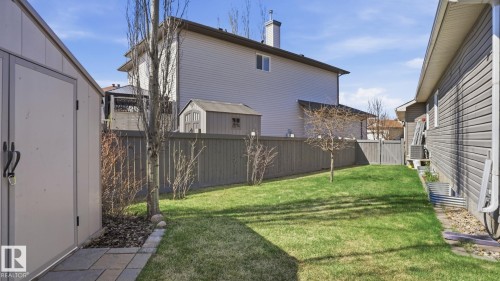 Expansive fenced backyard featuring a manicured lawn, established trees, and a functional storage shed - 5 Richelieu Place, Beaumont, AB - Outdoor