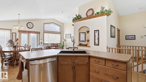 Kitchen island featuring a stainless steel dishwasher, an undermount black sink with a gooseneck faucet, and ample cabinetry - 5 Richelieu Place, Beaumont, AB - Indoor