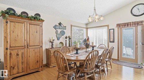 Dining area featuring light wood-finish flooring, vaulted ceilings, and a corner window arrangement with horizontal blinds - 5 Richelieu Place, Beaumont, AB - Indoor Photo Showing Dining Room