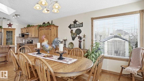Dining area featuring wood-finish flooring, a large window with blinds, and a skylight - 5 Richelieu Place, Beaumont, AB - Indoor Photo Showing Dining Room