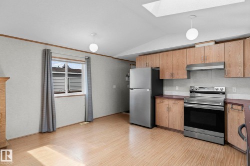 Kitchen area featuring wood-finish flooring, light wood cabinetry, stainless steel appliances, a white ceiling, and a skylight - 623 Evergreen Park, Edmonton, AB - Indoor Photo Showing Kitchen
