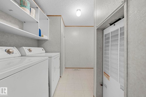 Dedicated utility area featuring built-in shelving, tiled flooring, and an integrated appliance space - 623 Evergreen Park, Edmonton, AB - Indoor Photo Showing Laundry Room