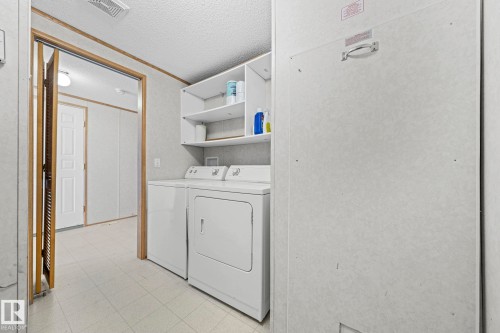 Dedicated laundry area featuring a white washing machine, dryer, and built-in white shelving - 623 Evergreen Park, Edmonton, AB - Indoor Photo Showing Laundry Room