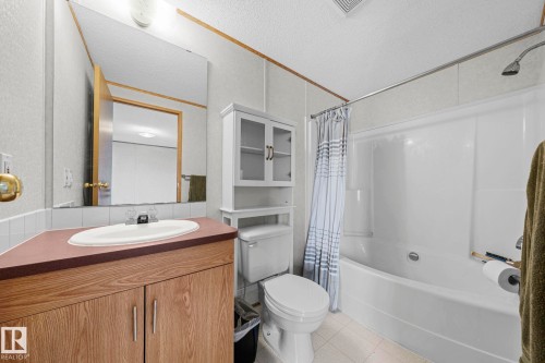 Bathroom featuring a wood-finish vanity with an integrated sink, a large wall mirror, and a white shower/tub combination - 623 Evergreen Park, Edmonton, AB - Indoor Photo Showing Bathroom