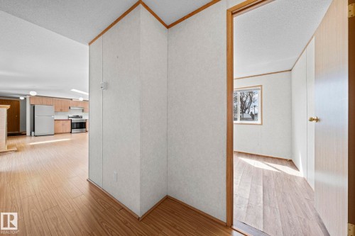 Open-concept interior featuring wood-finish flooring, light-toned wall panels, and contrasting wood trim - 623 Evergreen Park, Edmonton, AB - Indoor Photo Showing Other Room