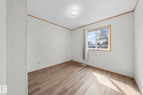 Bright interior space featuring wood-finish flooring, white panel walls, and a large window with white trim - 623 Evergreen Park, Edmonton, AB - Indoor Photo Showing Other Room