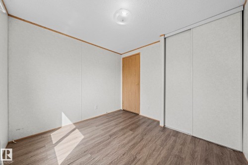Room featuring wood-finish flooring, light-toned walls, a flush-mount ceiling light fixture, a light wood door, and a built-in sliding panel closet - 623 Evergreen Park, Edmonton, AB - Indoor Photo Showing Other Room