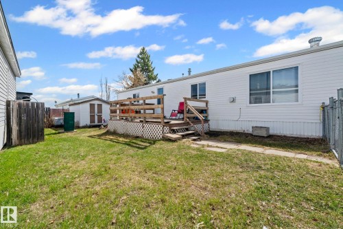 Rear exterior featuring white horizontal siding, a wooden deck with railing, a small outbuilding, and a chain-link fence - 623 Evergreen Park, Edmonton, AB - Outdoor With Exterior