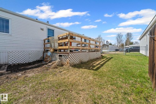 Rear exterior featuring a wood deck with wood railings, white lattice skirting, and a partial chain-link fence - 623 Evergreen Park, Edmonton, AB - Outdoor With Deck Patio Veranda