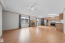 Open-concept living space with wood-finish flooring, a built-in fireplace, and a kitchen featuring wood cabinetry and stainless steel appliances - 623 Evergreen Park, Edmonton, AB  - Indoor 