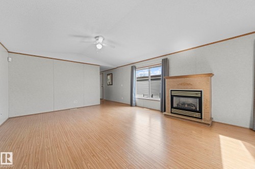 Living area featuring wood-finish flooring, a built-in fireplace with a stone surround and wood mantel, and a ceiling fan with integrated lighting - 623 Evergreen Park, Edmonton, AB - Indoor With Fireplace