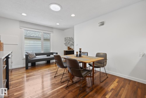 This bright dining area features rich hardwood flooring, a large window with a roller blind, and recessed lighting in the ceiling - 9736 78 Avenue, Edmonton, AB - Indoor Photo Showing Dining Room