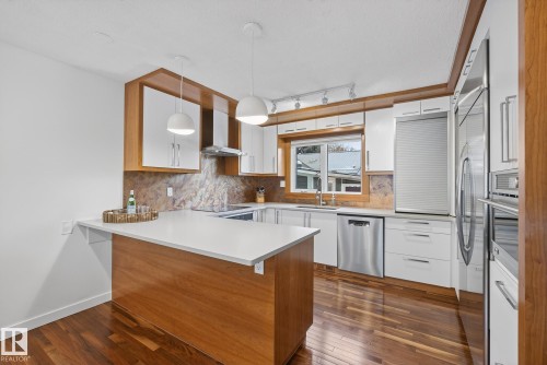 The kitchen features hardwood floors, white cabinetry with wood accents, stainless steel appliances, and a window above the sink - 9736 78 Avenue, Edmonton, AB - Indoor Photo Showing Kitchen With Upgraded Kitchen