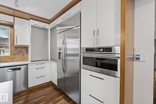 The kitchen offers white cabinetry, stainless steel appliances, and rich wood flooring - 9736 78 Avenue, Edmonton, AB - Indoor Photo Showing Kitchen