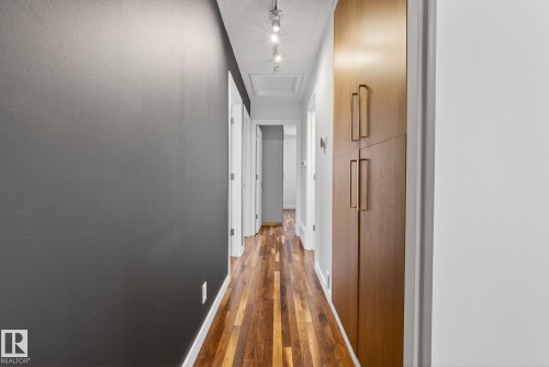 Hallway featuring hardwood floors, modern ceiling track lighting, and a built-in storage cabinet with contemporary hardware - 9736 78 Avenue, Edmonton, AB - Indoor Photo Showing Other Room