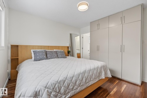 Bedroom featuring hardwood floors, a light-colored built-in wardrobe, and a contemporary ceiling light fixture - 9736 78 Avenue, Edmonton, AB - Indoor Photo Showing Bedroom