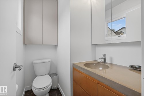 Bathroom featuring a toilet, built-in storage cabinets, a vanity with an integrated sink, and a mirrored medicine cabinet - 9736 78 Avenue, Edmonton, AB - Indoor Photo Showing Bathroom